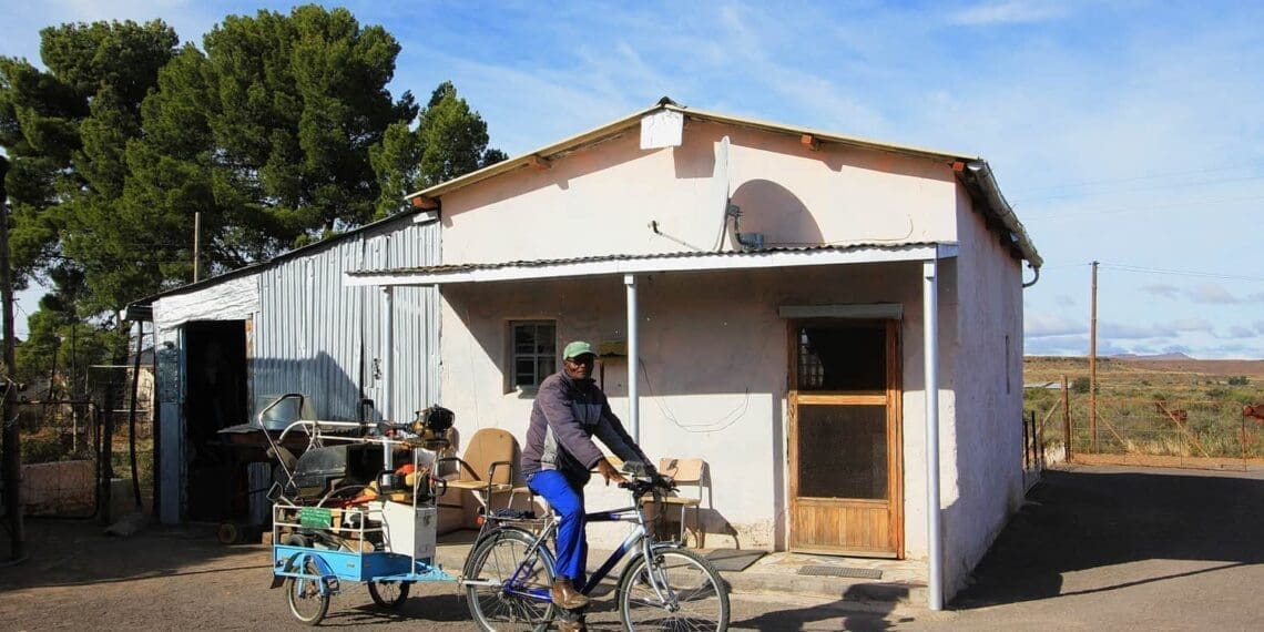 Max Ndamane, with the bicycle-drawn trailer he made for his gardening services in Richmond, in front of the old ramstal he turned into a home. Photo: Chris Marais