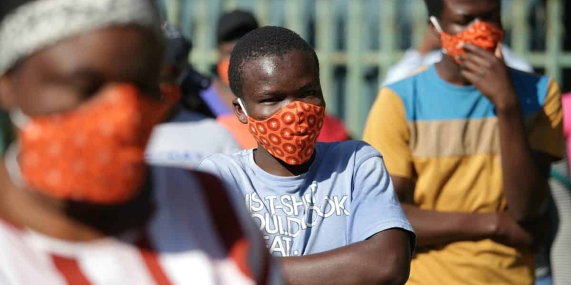 Community members wearing protective face masks as they queue for aid in Zandspruit informal settlement, north of Johannesburg. Phill Magakoe/AFP via Getty Images