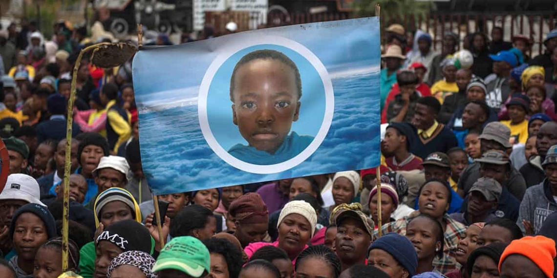 Coligny residents during an earlier march with a childhood image of Faki Mosweu. Photo: International Business Times