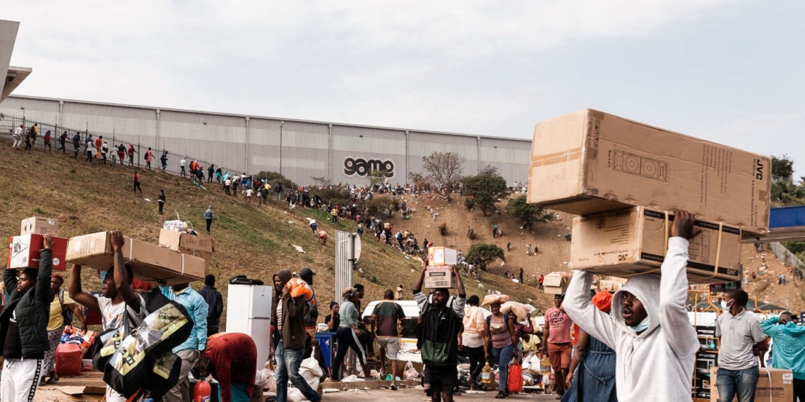 Suspected looters carry goods from the Game Warehouse in Durban on 13 July 2021. President Cyril Ramaphosa deployed troops in a bid to quell unrest that has claimed at least 50 lives. Photo: AFP