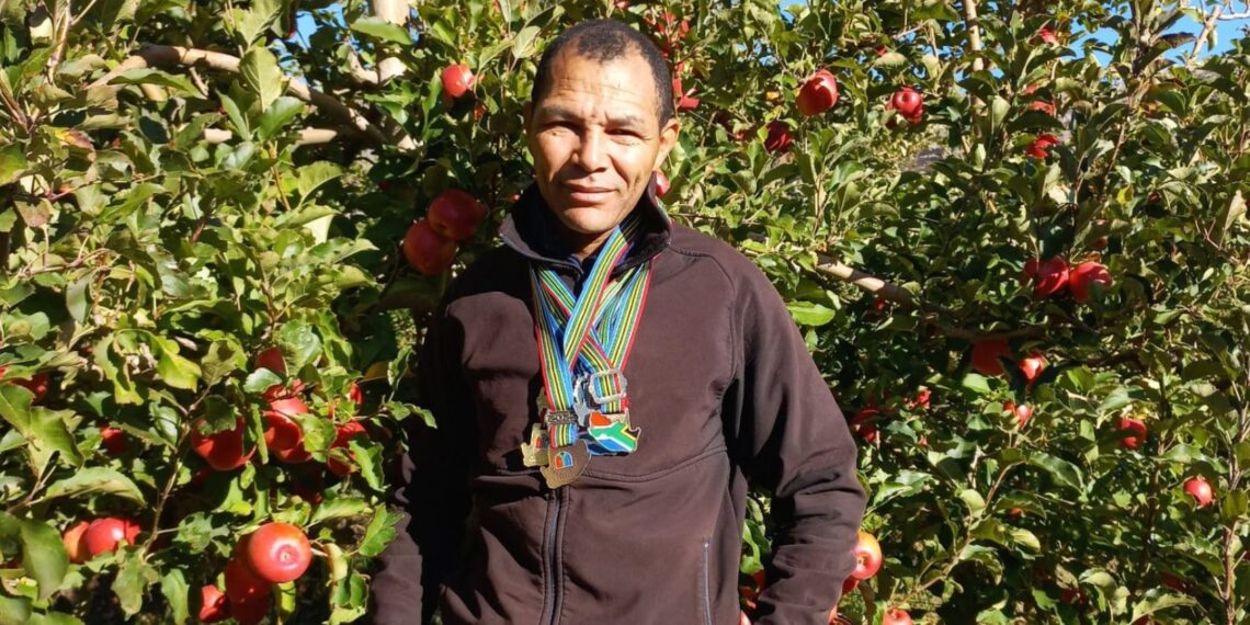 Jakob Volmoer stands proudly in a Rosy Glow orchard with the six medals he earned at
the South African Athletics Championship. Photo: Tru-Cape